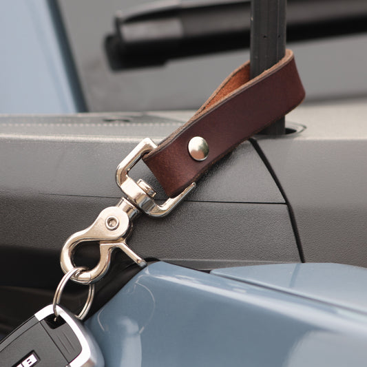The Clutch keychain in Brown, suede back detail color::Brown;