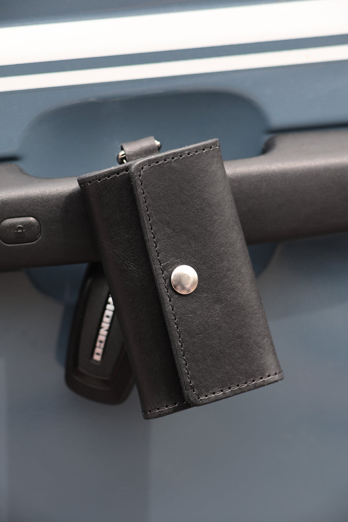 The Fort Wayne trifold key wallet in Black on a car door